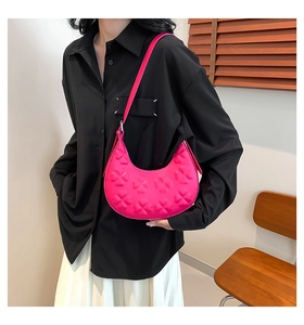 Détail du sac demi-lune fuchsia avec motif trèfle en relief porté par un mannequin