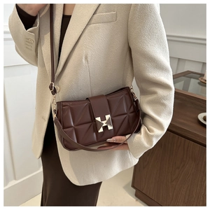 Detail of a brown quilted leather underarm bag featuring a classic gold H-shaped buckle