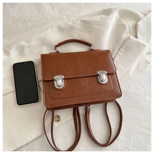 Vue à plat d'un sac à dos vintage en cuir PU marron avec boucles argentées et un téléphone