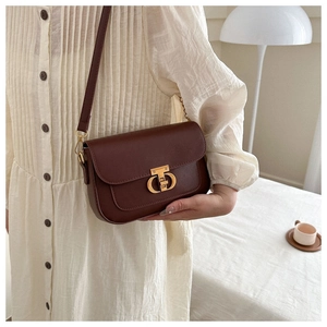 Détail du petit sac bandoulière en cuir marron foncé avec fermoir logo en métal doré vieilli