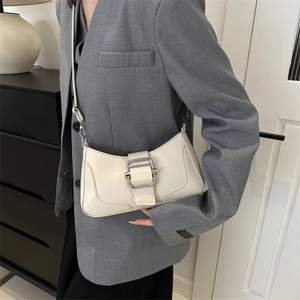 Sac baguette chic en cuir crème avec boucle argentée porté sur une veste de blazer grise