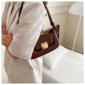 Detail of dark brown leather underarm bag with knot strap and gold magnetic buckle