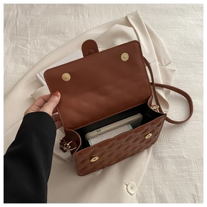 Detail view of the open brown quilted handbag showing interior space and magnetic clasp