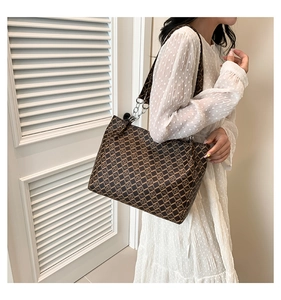 Detail of a large brown geometric pattern tote bag with metal chain and wide fabric strap