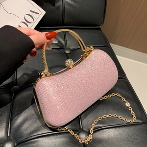 Pochette de soirée rose pailletée avec poignée dorée et bandoulière sur siège noir