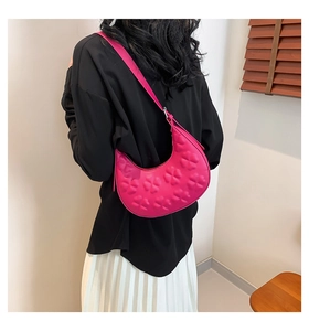 Detail of fuchsia crescent shoulder bag featuring 3D embossed clover patterns