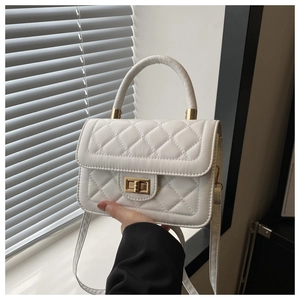 Vue détaillée de la texture matelassée blanche et du fermoir rotatif doré du sac