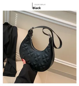Close-up of black hobo bag with embossed clover pattern and adjustable wide strap