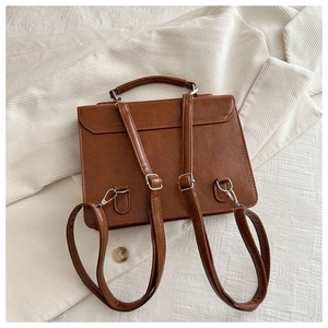 Détail des bretelles réglables et boucles argentées sur un sac à dos en cuir vintage