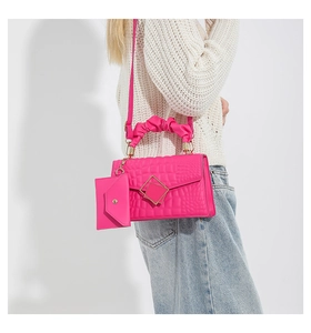 Detail of rose pink crocodile pattern handbag with gold clasp and mini envelope pouch