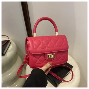 Détail d'un sac matelassé rose avec fermoir en métal doré et poignée supérieure