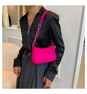 Detail of fuchsia underarm bag with grainy leather texture and chunky chain strap decor