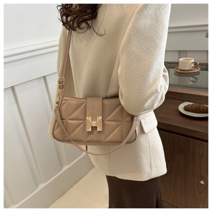 Quilted khaki shoulder bag with H-buckle detail shown worn over a model's shoulder