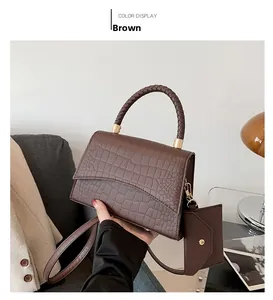 Detail of brown crocodile pattern handbag with woven handles and small matching purse