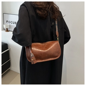 Close-up of vintage brown leather Boston bag with a patterned ethnic style wide strap