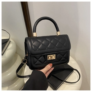 Détail d'un sac à main matelassé noir avec fermoir doré sur un support géométrique
