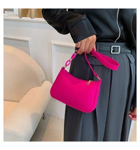 Macro view of rose red faux crocodile leather shoulder bag with gold metal zipper detail