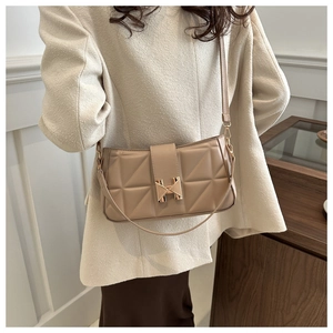 Detailed close-up of beige quilted leather handbag featuring a golden H-shaped clasp