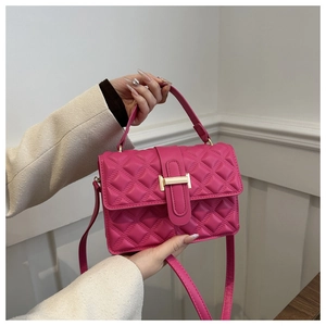 Detail of magenta quilted handbag featuring a gold metal buckle and leather handle