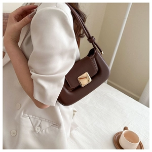Detail of dark brown leather shoulder bag featuring gold square buckle and knot strap
