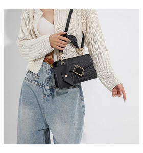 Detail of black crocodile texture handbag with gold hardware and mini pouch charm
