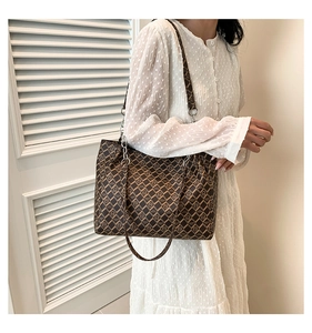 Detail of coffee brown monogram tote bag with chain strap and vintage grid pattern