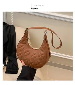 Close-up of brown crescent bag featuring elegant embossed clover patterns and textures