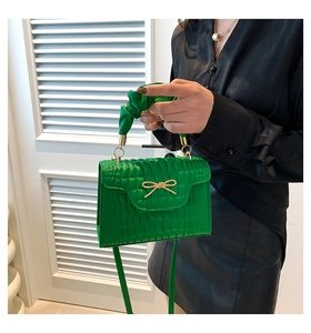 Détail du sac à main vert à motif crocodile avec poignée froncée et boucle dorée