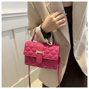 Detail of rose red quilted crossbody bag with gold metal clasp on beige tweed jacket