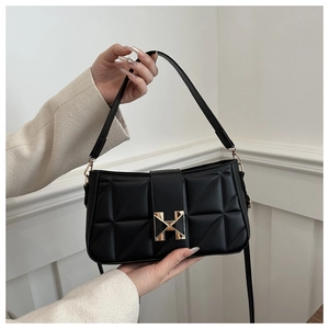 Close-up of black quilted leather bag featuring a geometric gold clasp and dual straps