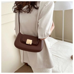 Detail of a dark brown leather shoulder bag with a gold metal buckle on a model