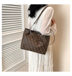 Brown monogram tote bag detail with leather strap and silver chain on model in white dress