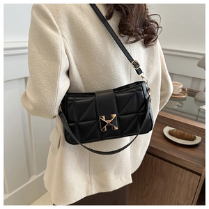 Close-up of black quilted shoulder bag with gold H-shaped buckle and luxury leather texture