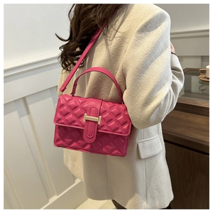Detail of magenta quilted handbag featuring a golden H-shaped clasp and crossbody strap