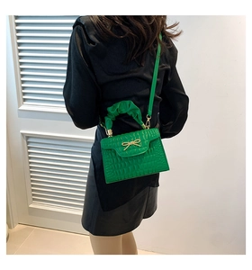 Detail of green faux crocodile skin bag with pearl bow and ruched handle detail