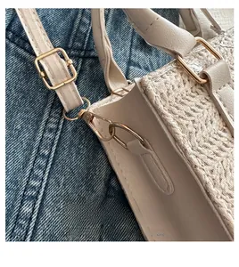 Detail of adjustable shoulder strap and gold-tone metal hook on straw crossbody bag