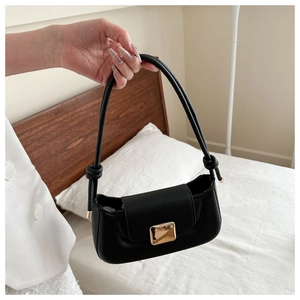 Detail of black faux leather underarm bag with gold square buckle and knotted handle design