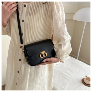 Détail d'un sac besace chic en cuir noir mat avec un élégant fermoir doré à double cercle