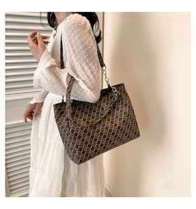 Brown vintage printed tote bag with leather chain strap shown on model's shoulder