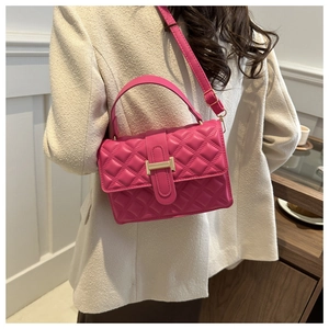 Detail of rose pink quilted crossbody bag with golden H-clasp and top handle shown on model