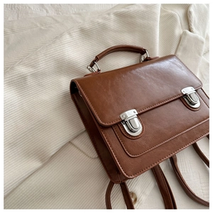 Gros plan d'un sac à dos vintage en cuir marron avec boucles en métal sur velours côtelé