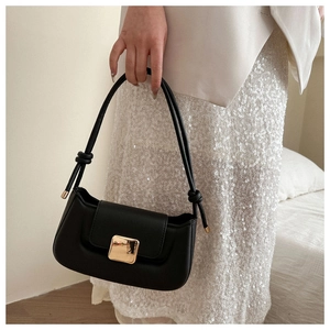 Detail of a black faux leather baguette bag featuring a square gold metal clasp