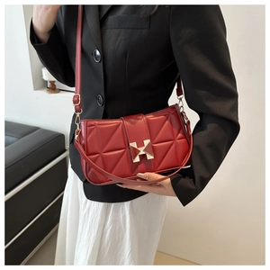 Fashionable red embossed shoulder bag with gold H-buckle shown on a model