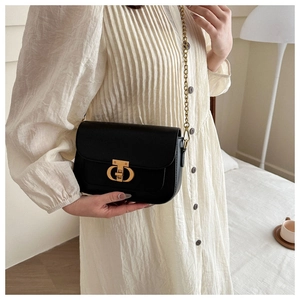 Détail d'un sac bandoulière noir chic avec boucle métallique dorée et bandoulière chaîne