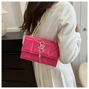 Fuchsia quilted crossbody bag with gold chain and tassel on white textured shirt