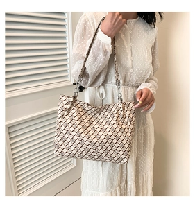Macro shot of stylish beige tote bag with chain strap and vintage pattern detail