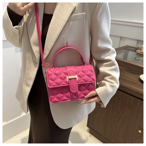 Detail of bright pink quilted crossbody bag with gold metal trim on beige wool blazer