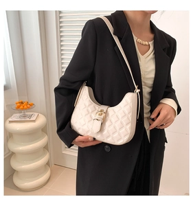 Detail shot of a white quilted leather hobo bag with a gold metal buckle on a shoulder