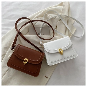 Detail of vintage PU leather crossbody bags with golden double-ring buckle on white blazer