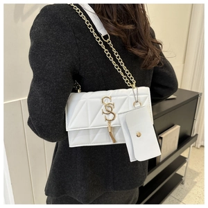 Détail du sac blanc en similicuir matelassé avec logo doré, pompon et chaîne